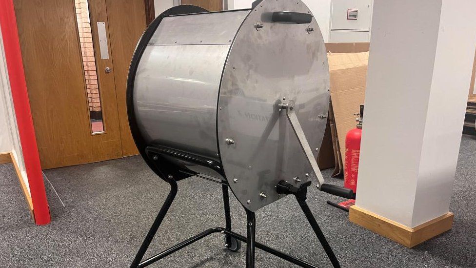 Large metal drum on a stand with a crank handle to the side