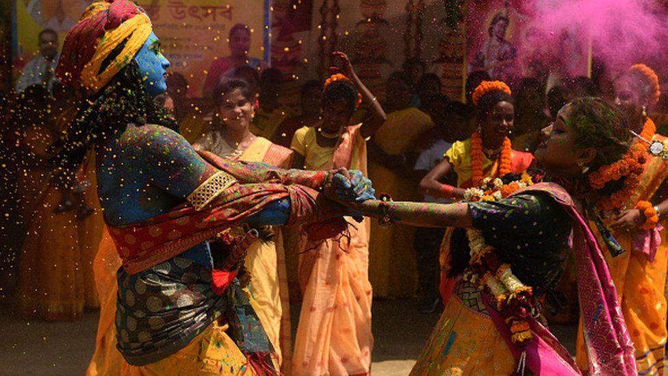 People dressed as Hindu deity Lord Krishna and Radha smeared with coloured powder, dance to celebrate Holi festival on March 17, 2022 in Kolkata, India.