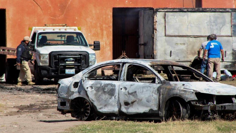 The burnt wreckage of a car stands at the scene where members of an armed group opened fire to partygoers attending a posada, in Salvatierra, in Guanajuato state, Mexico, December 17, 2023.