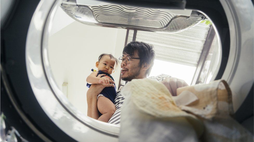 Man and toddler filling up tumble dryer