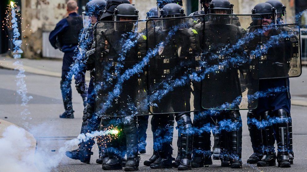 Police in riot gear stand use their shields to deflect a firework during a May Day rally marking International Workers' Day, in Nantes, France.