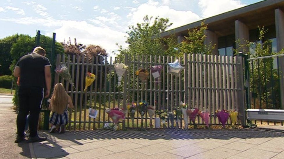 Floral tributes pinned to school fencing