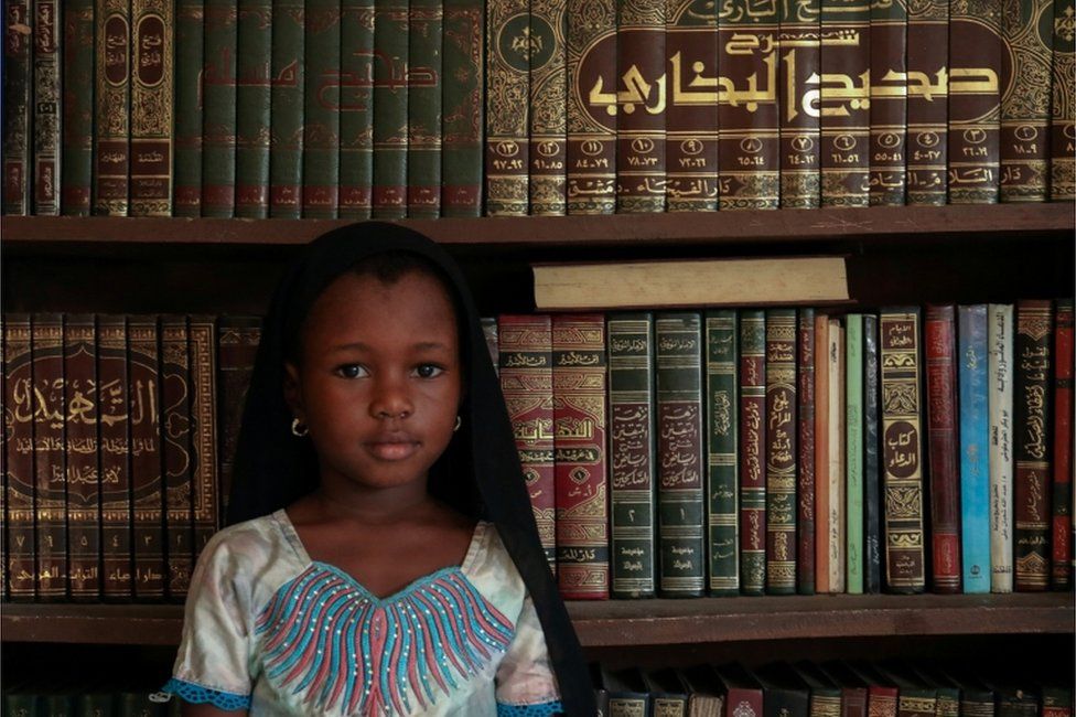 Kadiatou Diallo poses next to religious books during the first day of the Mulsim holy month of Ramadan, in Abidjan, Ivory Coast on 24 April.