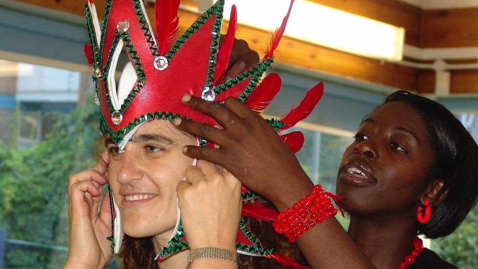 A red crown-style head-dress being fitted