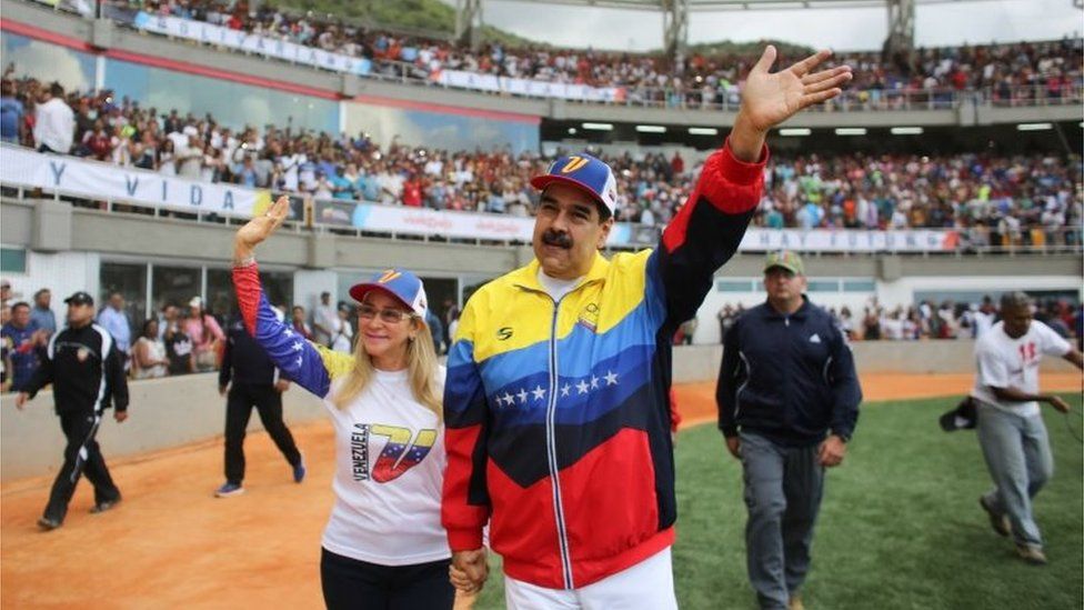 Nicolás Maduro waves to the crowd while walking next to his wife Cilia Flores