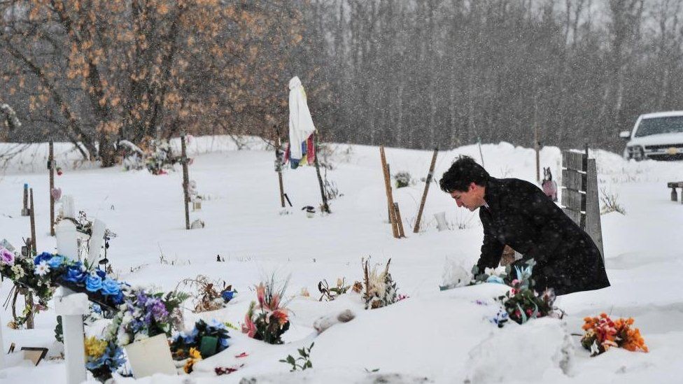 Justin Trudeau lays flowers amid snow at the graves of victims of a September stabbing spree in Saskatchewan