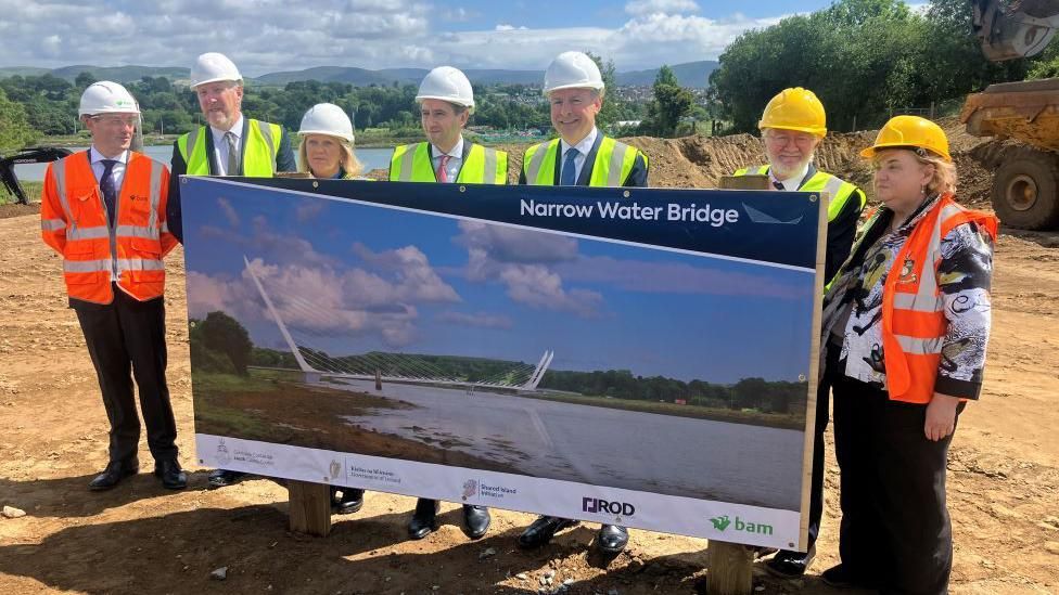 Taoiseach Simon Harris, Tanaiste Michael Martin and NI Infrastructure Minister John O'Dowd stand with others at the breaking of ground at the Narrow Water Bridge 