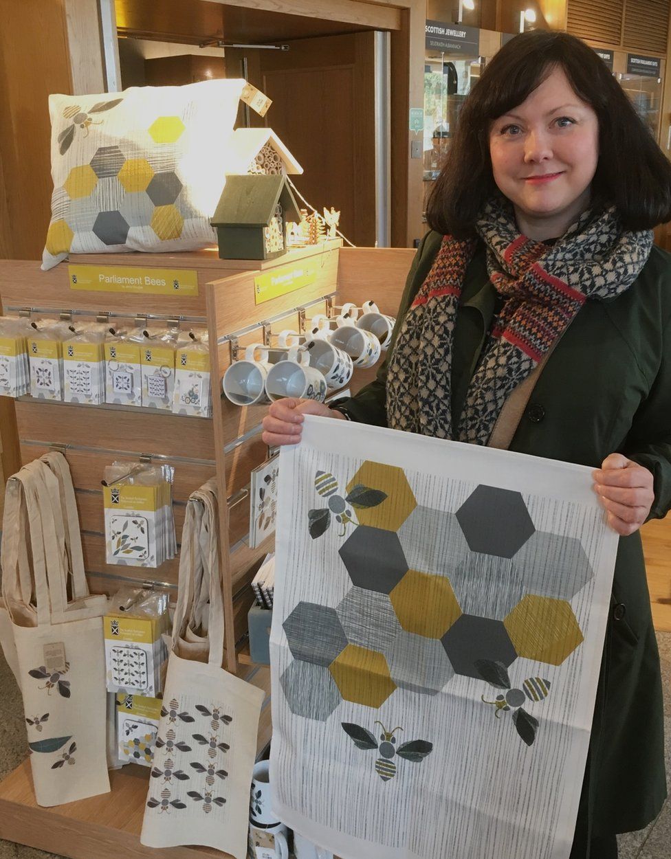 Jenni Douglas holding merchandise featuring her art in the Scottish Parliament shop