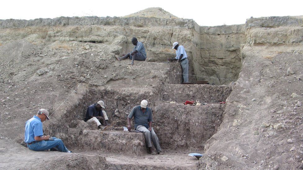 Five men work in a stepped excavation area