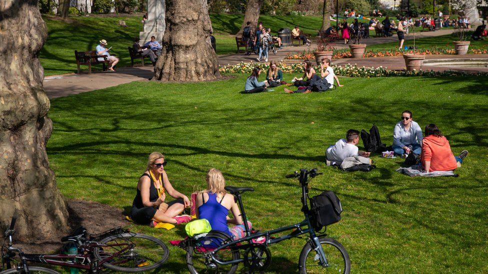 People relax in the sun at Victoria Embankment Gardens, Central London