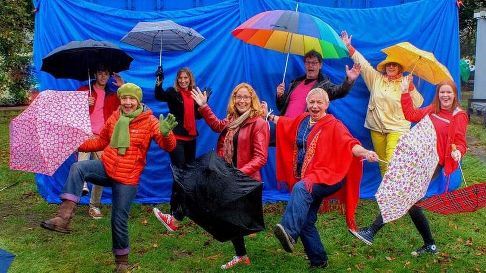 Caroline Page with a group of people holding umbrellas