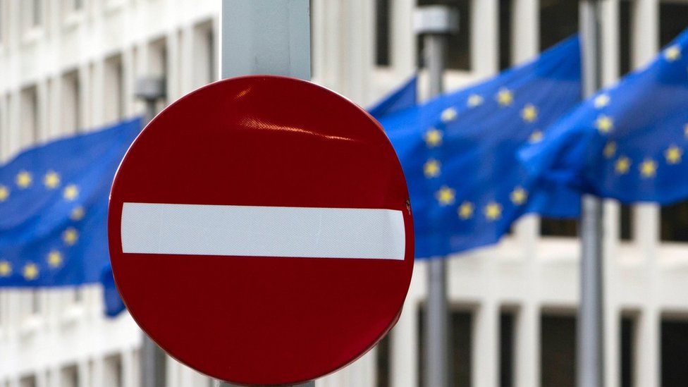 EU flags flutter in the wind in back of a no entry street sign in front of EU headquarters in Brussels on Friday, June 24, 2016.