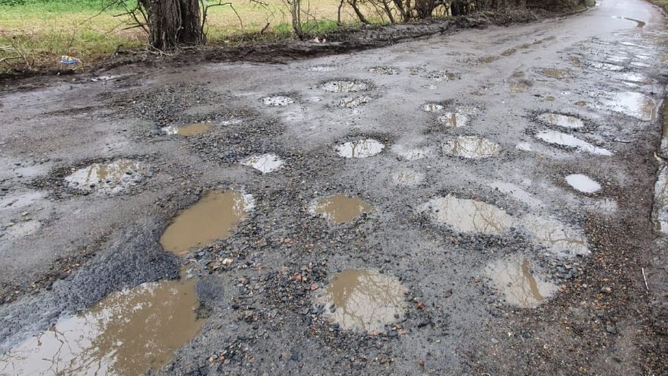 The rural road near Harlow in Essex has many potholes