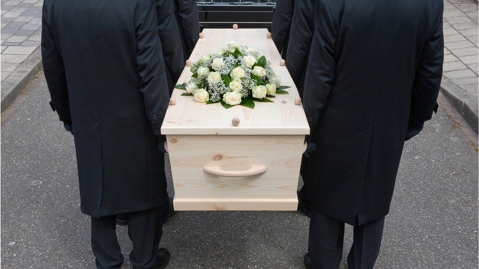 Pallbearers carry coffin