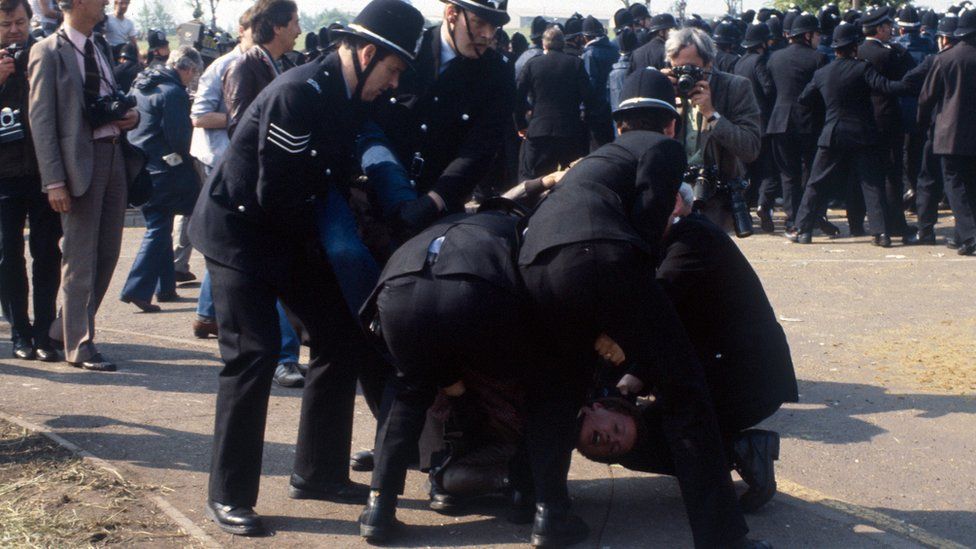 Policemen wrestling a striking miner to the ground