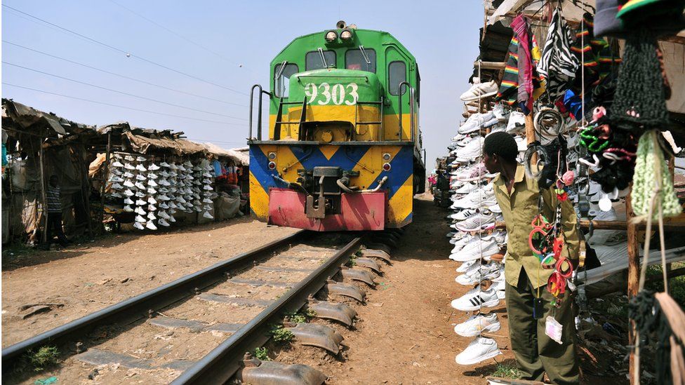 A Kenyan, selling second-hand shoes, on 18 September looks at a moving train in the Sinai slum of Nairobi.