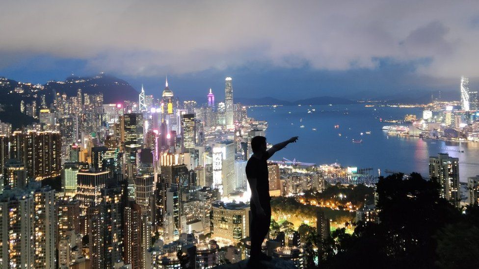 Qingfeng stands in front of a lit-up Hong Kong skyline