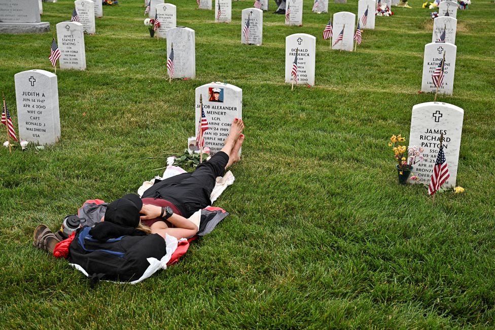 Krista Meinert lies at the grave of her son, Jacob Meinert ,in Section 60 at Arlington National Cemetery on Memorial Day in Washington, U.S. May 29, 2023.