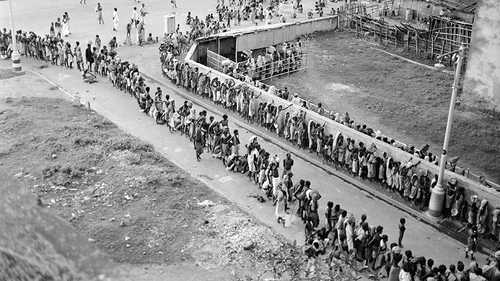 Long queue for a soup kitchen winds round a street in Kolkata