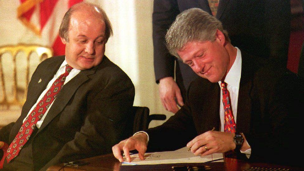 James Brady, left, watches as Bill Clinton signs the Brady Law