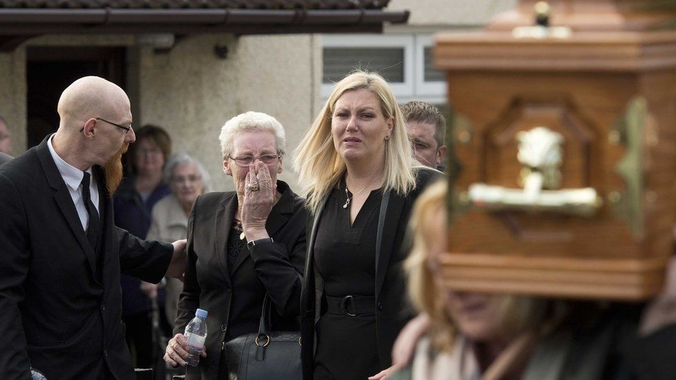 Mourners comfort each other at the funeral of Seamus Wright