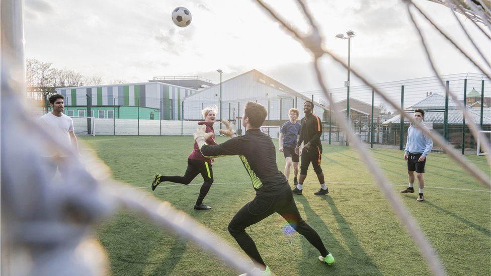 A group of young men playing football on an artificial pitch