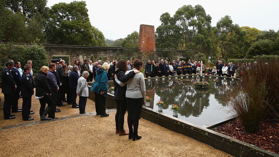 People stand at the Port Arthur memorial site during a commemoration service in 2016 to mark the 20th anniversary of the massacre