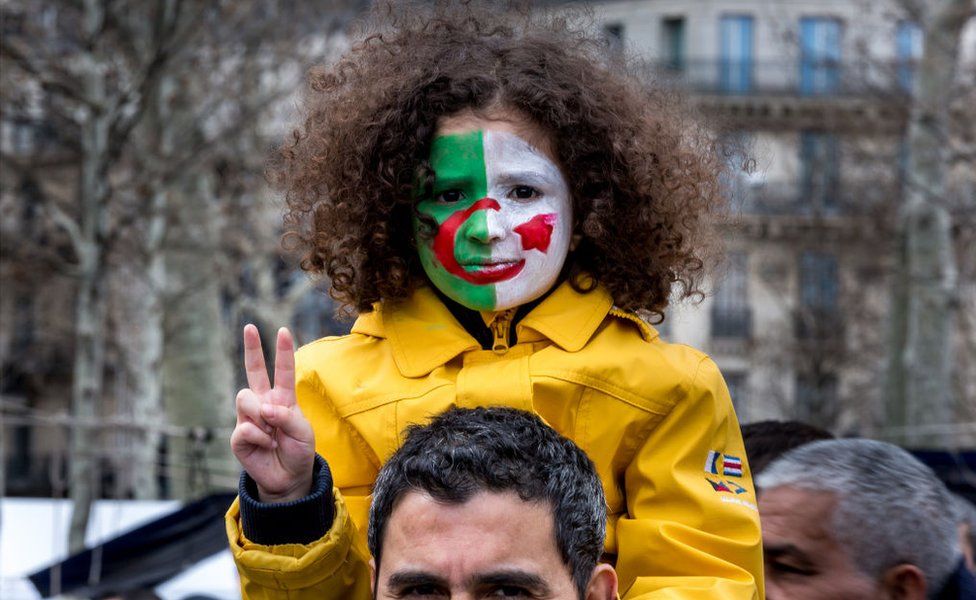 A young girl is seen with an Algerian flag painted on her face sitting on the shoulders of her father during a demonstration against Algerian President Abdelaziz Bouteflika in Place de la République on 17 March 2019 in Paris.
