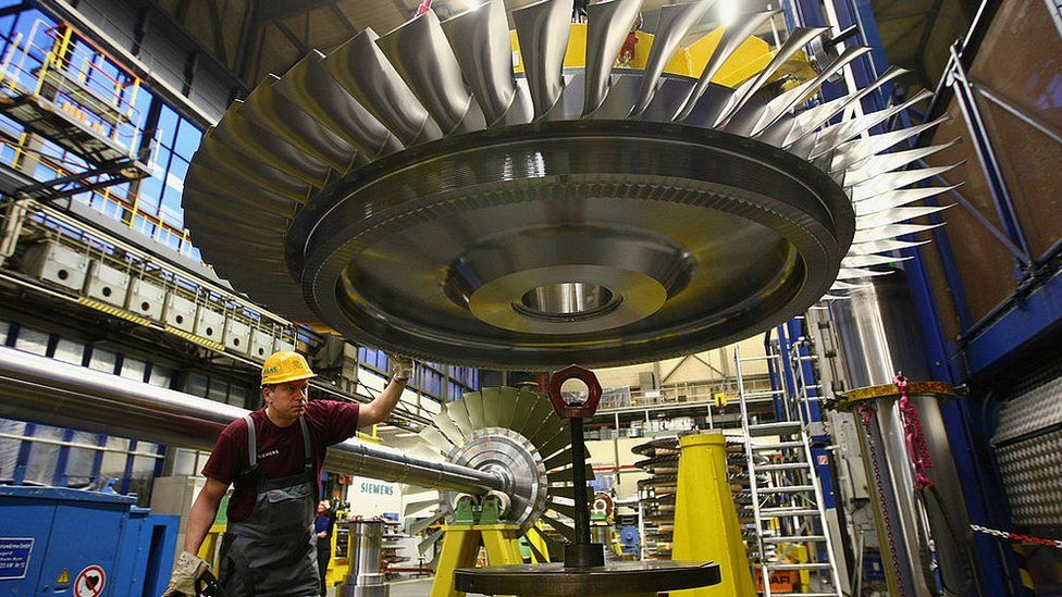 A worker uses a remote control to guide a rotor assembly for a turbine at the Siemens gas turbine factory