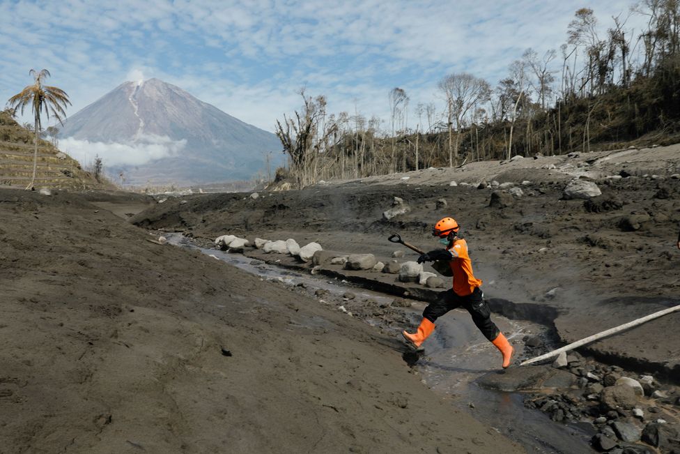 A rescue worker jumps across the lava flow in an area devastated by the eruption of Mount Semeru, in Lumajang, Indonesia, 8 December 2021.
