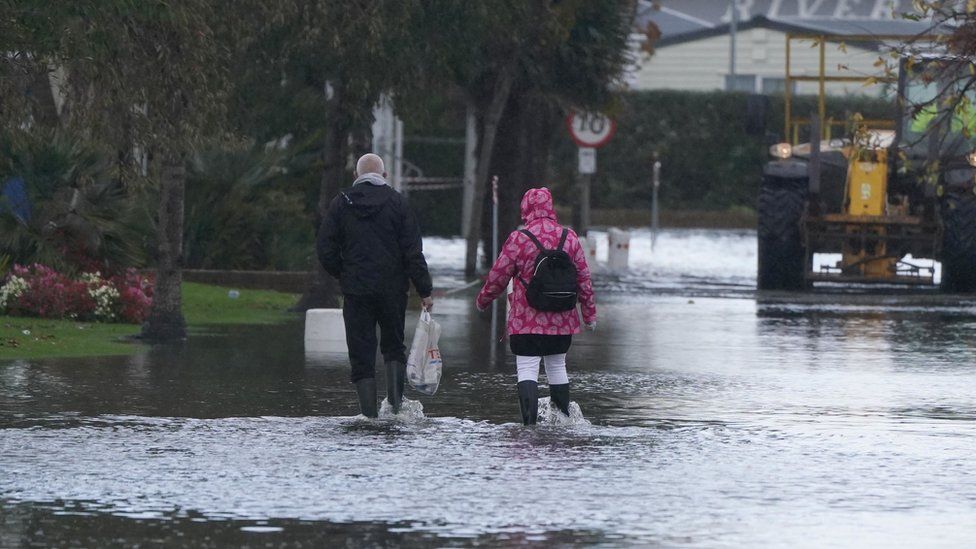 People walk through flood water at Riverside Caravan Centre in Bognor Regis, West Sussex, after heavy rain the area.