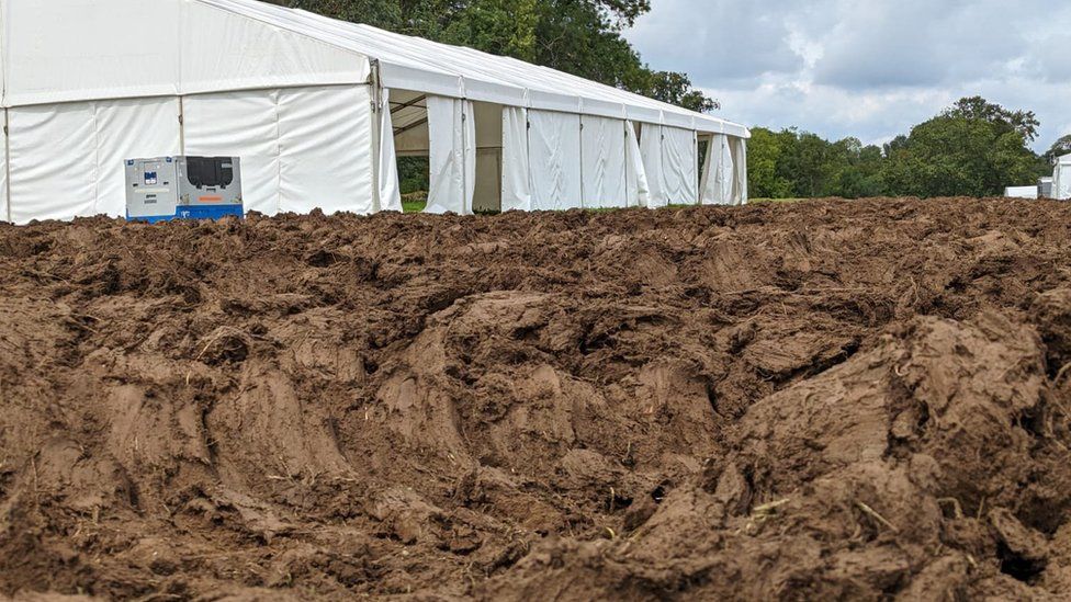 Churned up ground and a white marquee