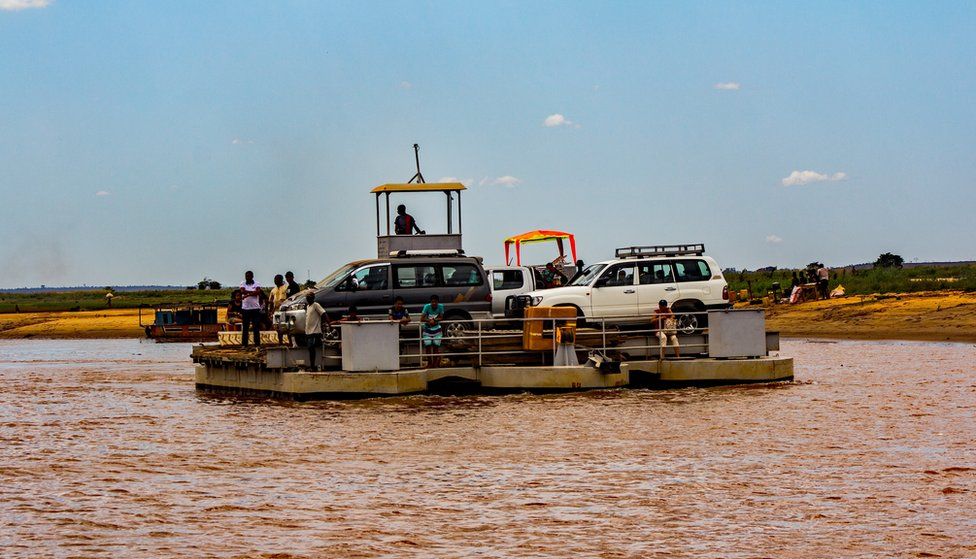 A floating raft carries vehicles and people across the river