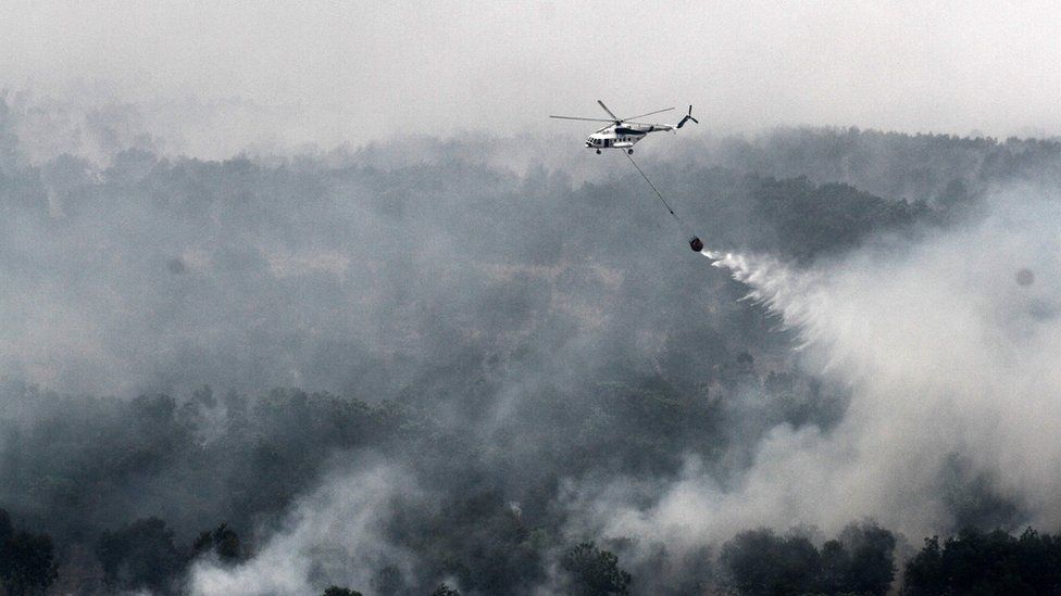 A MI-17 helicopter run by the Indonesian National Disaster Mitigation Agency conducting water-bombs on a fire spot in Ogan Komering Ilir area in South Sumatra province on 17 October 2015.