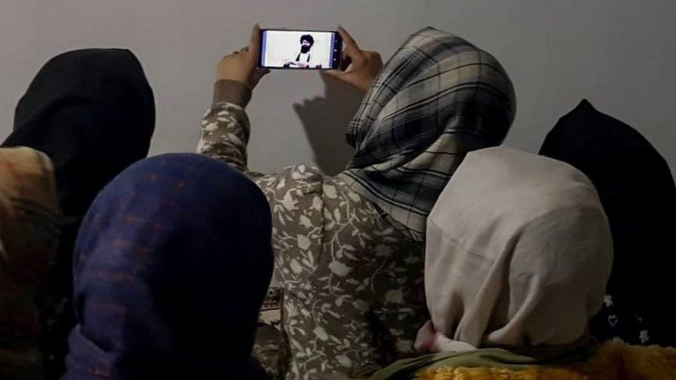 Afgańskie kobiety oglądają przemówienie talibskiej minister ds. szkolnictwa wyższego Nidy Muhammad Nadeem przez telefon komórkowy w Kabulu, Afganistan, 22 grudnia 2022 r.