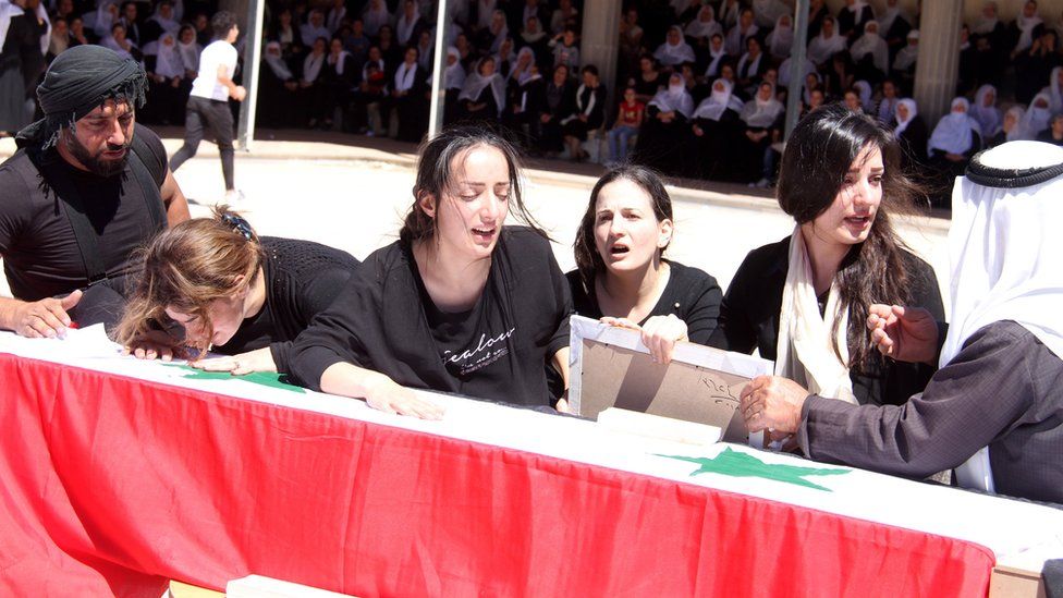 Relatives mourn beside the coffin of a person killed in an IS attack in Suweida province, Syria (27 July 2018)