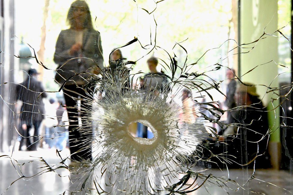 People look at a bullet hole in a window near to the Marks and Spencer on the Champs Elysees in Paris following the shooting of a police officer, 21 April