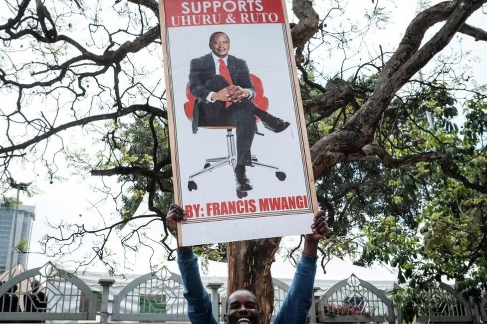A supporter holds a banner bearing a picture of President Uhuru Kenyatta as they celebrate on November 20, 2017 in Nairobi after Kenya"s Supreme Court dismissed two petitions to overturn the country"s October 26 presidential election re-run, validating the poll victory of Kenyatta.