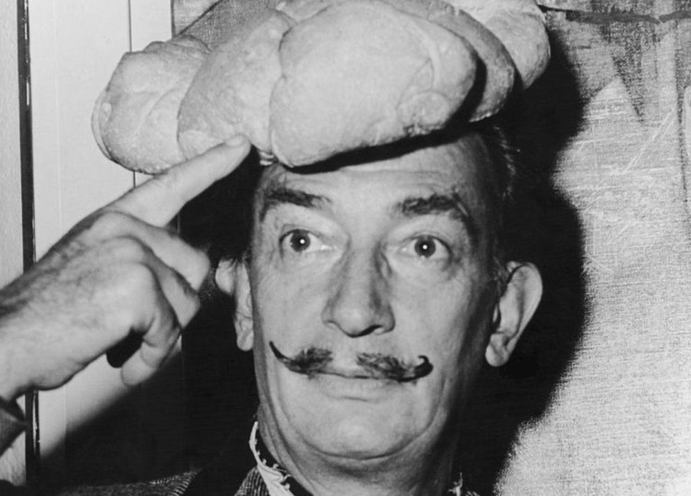 Spanish surrealist artist Salvador Dali wears a hat shaped like a loaf of bread on his head, 5 November 1958