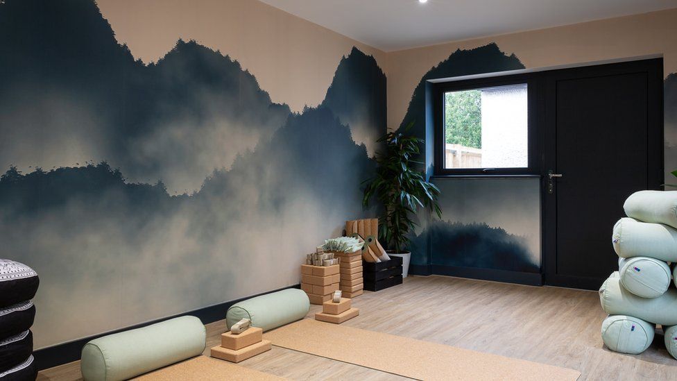 Yoga studio with mats rolled out and a mountain scene mural on the walls.