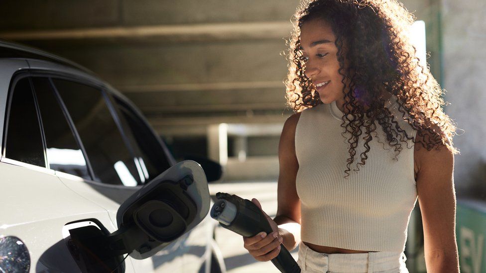 Stock shot of women charging electric ar