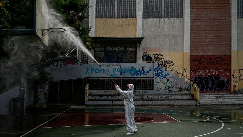 A municipality worker disinfects a high-school yard in Athens