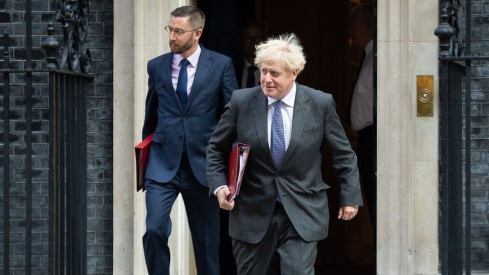 Simon Case, the head of the civil service, exiting Downing Street with Boris Johnson in 2020