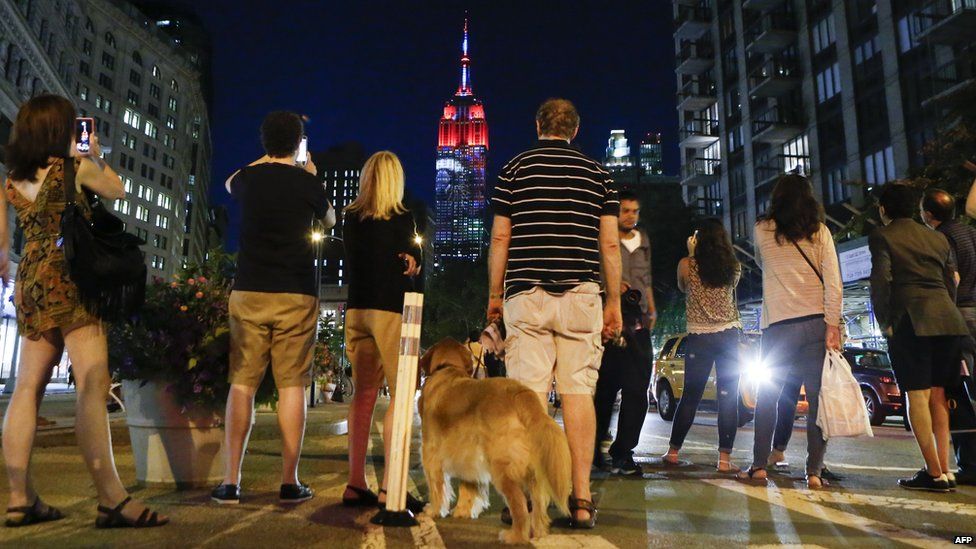 People watch a projection on the Empire State Building on 1 August 2015