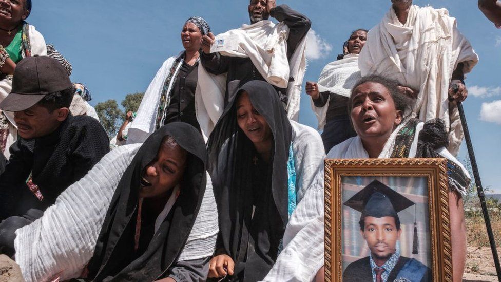 People mourn at a mass grave containing the bodies of 81 in the city of Wukro, north of Mekelle, on 28 February 2021