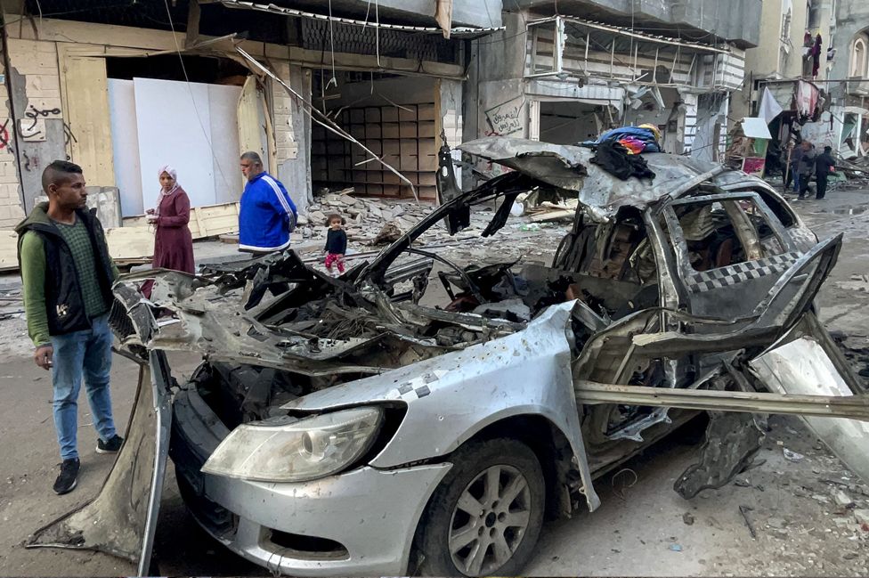 Onlookers check the car in which three sons of Hamas leader Ismail Haniyeh were reportedly killed in an Israeli air strike in al-Shati camp, west of Gaza City on 10 April 2024