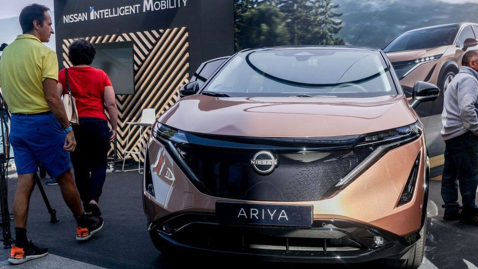 People looking at a Nissan Ariya electric car