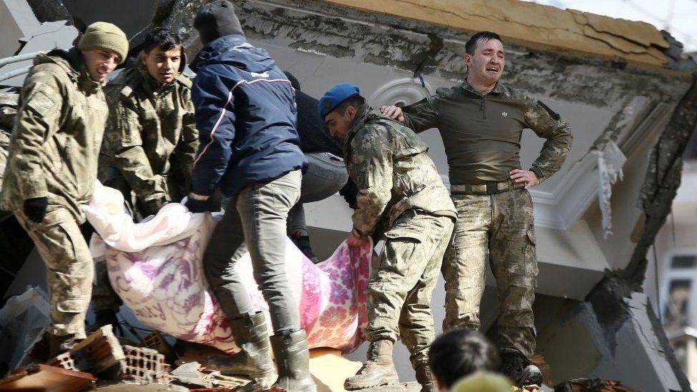 Members of the Turkish military pull two women from under the rubble of a collapsed building in Hatay