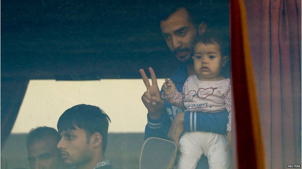 A migrant flashes a victory sign from inside a bus at Bicske railway station, Hungary, September 4, 2015.