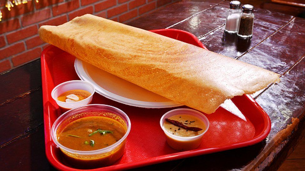A plate of dosa with sambar and chutney